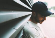 여름철 자외선으로부터 모발 보호법 man wearing black cap and white shirt leaning on gray metal wall